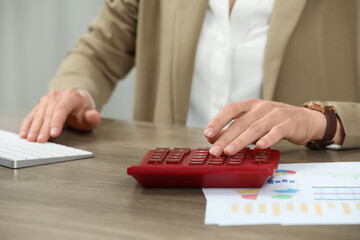 Poster - Professional accountant using calculator at wooden desk in office, closeup