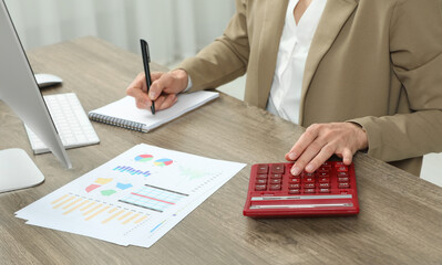 Poster - Professional accountant using calculator at wooden desk in office, closeup