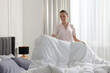 Young beautiful woman making bed in room