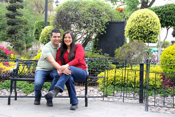 40 year old Latino man woman couple without children take a walk in the park and show their love on a bench