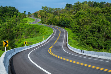 Wall Mural - long curvy forest asphalt road over the hills. beautiful curved road in the forest. side view of roa