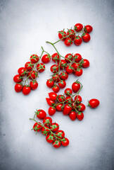 Wall Mural - Red cherry tomatoes on branches on gray table, food background, top view