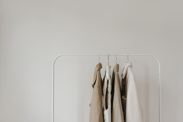 Wall Mural - Warm autumn seasonal women's clothes on hanger over white wall. Neutral beige jackets and coat. Minimalist fashion clothes wardrobe