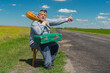 Portrait of bearded Ukrainian senior gestures while sitting  on summer roadside  with an ancient green suitcase and mandolin