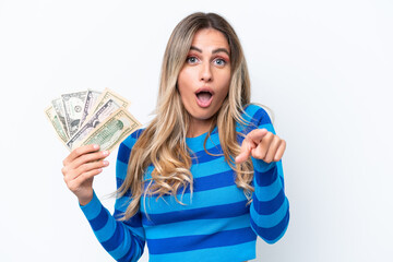 Canvas Print - Young Uruguayan woman taking a lot of money isolated on white background surprised and pointing front