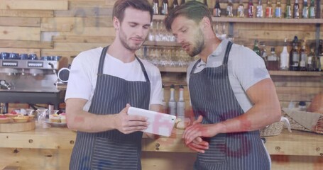 Poster - Animation of currency signs and numbers, caucasian male coworkers discussing over tablet in cafe