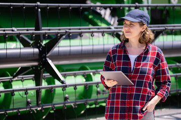Fototapete - Woman farmer with digital tablet on a background of harvester. Smart farming concept.