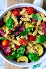 Canvas Print - Pasta with zuccini, tomato and salami and Basil  .top veiw.selective focus