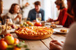 Thanksgiving family dinner. Traditional apple pie and vegan meal close up, with blurred happy people around the table celebrating the holiday.