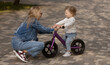 Young mother teaches her little son how to ride a balance bike in the park