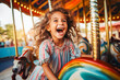 canvas print picture - A happy young girl expressing excitement while on a colorful carousel, merry-go-round, having fun at an amusement park