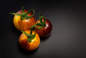 Wall Mural - Wet yellow-red striped tomatoes on black background