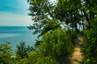 On a sunny Summer day, the view of a peaceful, blue Lake Michigan from atop a green forested bluff near Milwaukee, WI.