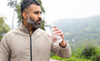 © ADDICTIVE STOCK - Bearded ethnic sportsman standing with drinking water bottle in daytime