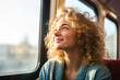 © MVProductions - Pensive young woman, happily gazing out the window during her morning commute on an urban light rail train, expressing gratitude