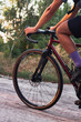 Closeup of cyclist riding on professional gravel bike on country road at sunset.