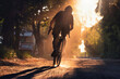 Silhouette of a cyclist on a gravel bike in a cloud of dust. Man riding a bicycle on a gravel road at sunset.