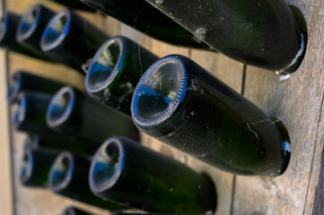 Walking in deep undergrounds caves with bottles on wooden racks, making champagne sparkling wine from chardonnay and pinor noir grapes in Epernay, Champagne, France