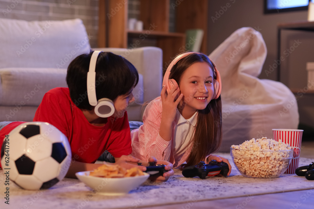 Little children playing video game at home in evening