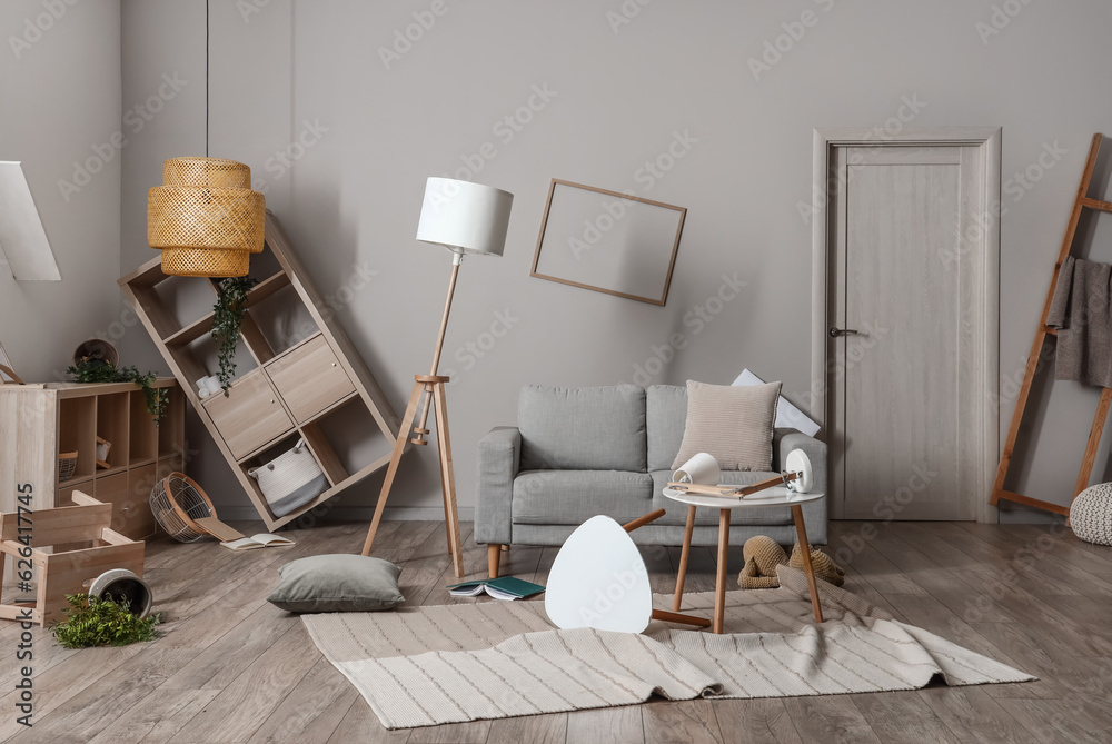 Sofa with tables and shelving units in messy living room