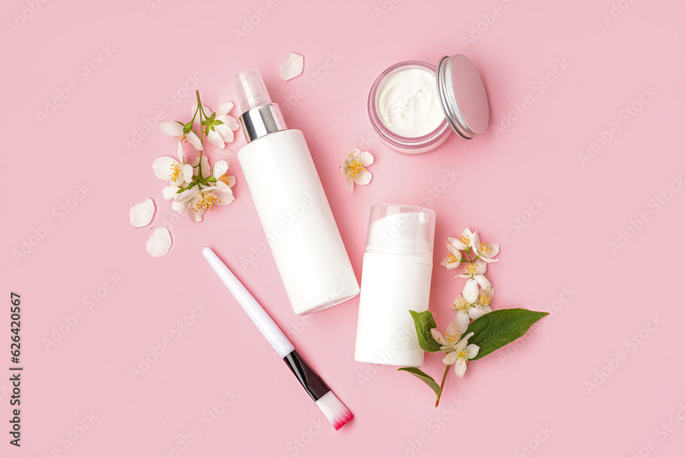 Composition with cosmetic products and beautiful jasmine flowers on pink background