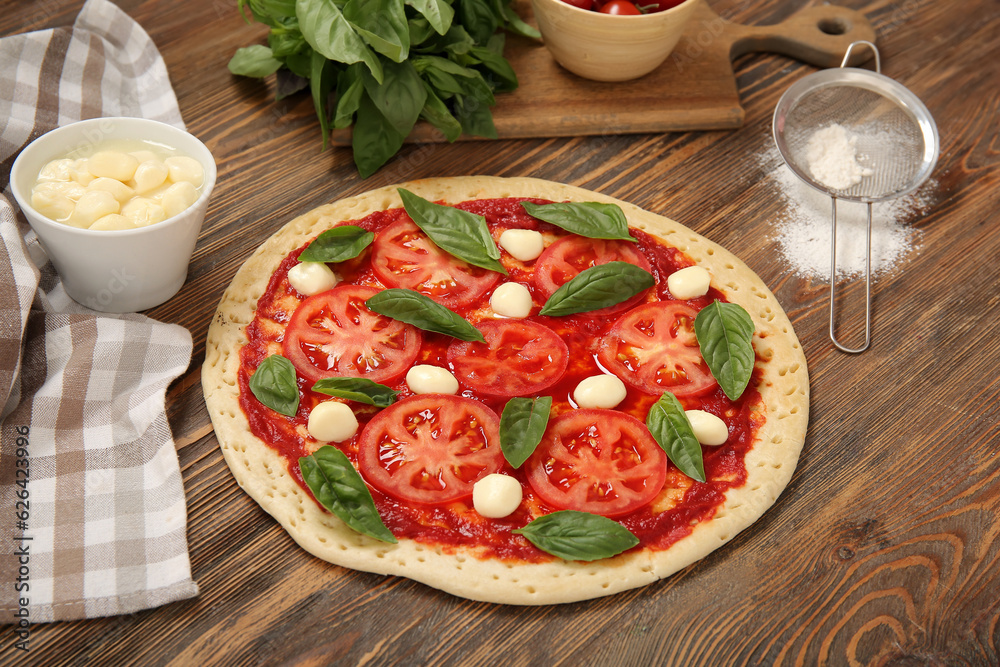 Tasty pizza and ingredients on wooden background