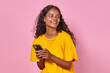 © antianti - Young laughing Indian woman student with phone surf internet and laugh exchanging witty messages with college friends and leaving short text posts on new social network stands posing in pink studio.