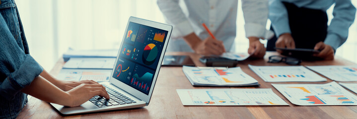 Fototapete - Panorama shot analyst team utilizing BI Fintech to analyze financial report with laptop. Businesspeople analyzing BI power dashboard displayed on laptop screen for business insight. Scrutinize