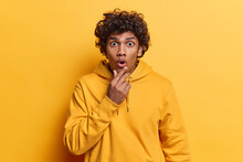 People Emotions. Studio Photo Of Young Surprised Hindu Male Student Looking Straight At Camera Shocked As If Seeing Something Unusual Or Unexpected Holding Left Hand Raised On Chin Standing Isolated