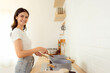 © Nutlegal - Beautiful caucasian woman cooking at kitchen Happy girl standing by stove in kitchen cooking and looking at camera Cooking delicious meal holding pan frying food with the pan in the kitchen at home