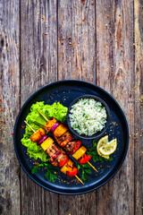 Poster - Meat skewers - grilled meat and pineapple with white rice and vegetables on wooden background
