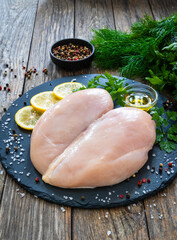 Wall Mural - Fresh raw chicken breasts on cutting board with spices on wooden background
