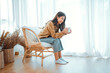 © oatawa - Happy asian woman relaxing drinking hot coffee or tea in holiday morning vacation on armchair at home, Cosy scene, Smiling pretty woman drinking hot tea in autumn winter. copy space.