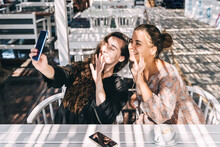 Two Female Friends Take A Selfie In A Summer Cafe