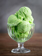 Pistachio green ice cream in a transparent bowl on a wooden background