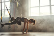 © Friends Stock - TRX Training. Young athletic woman in sports clothing training legs with trx fitness straps in the gym.