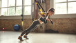 © Friends Stock - Working hard. Side view of young athletic woman with perfect body in sportswear doing push ups with trx fitness straps in the gym