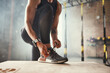 © Friends Stock - Preparing for workout. Cropped photo of beautiful young woman in sports clothing tying her shoelaces while exercising in gym.