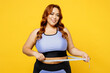 © ViDi Studio - Young chubby overweight plus size big fat fit woman wearing blue top warm up training hold measure tape on waist look camera isolated on plain yellow background studio home gym. Workout sport concept.