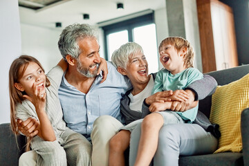 Wall Mural - grandchild family child grandparent grandfather happy together grandmother girl senior boy man woman smiling granddaughter grandson sofa