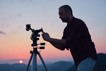 Wall Mural - astronomer looking at the sun with a telescope and using a cellphone.