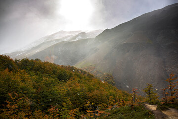 Wall Mural - Sun through cloudy and snowing sky over mountains in autumn,  W Trek in Torres Del Paine, Patagonia, Chili