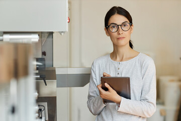 Wall Mural - Waist up portrait of young woman at modern factory wearing glasses and holding tablet, copy space