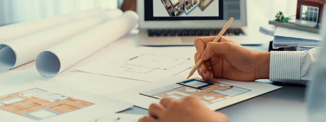 Interior architect designer at table designing hand drawing house interior blueprint sketch using architecture software, choosing mood board samples for modern precise house renovation design. Insight