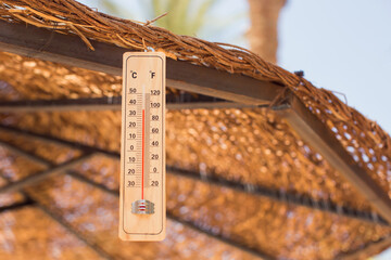 Fototapete - Thermometer on a parasol showing high temperature. Hot weather and climate concept
