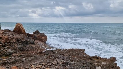 Wall Mural - Surf on the stones of the Mediterranean coast. High quality 4k footage