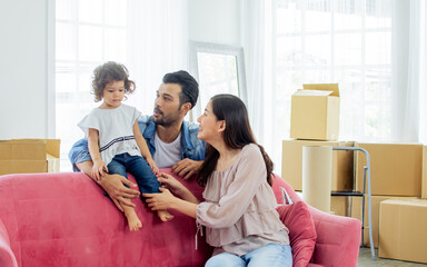 Happy family with three members Caucasian father, Asian mother and little daughter laughing, playing together to hug the girl with fun and happiness while moving to new house.