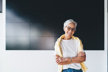 Cheerful senior professor standing near black monitor at lecture