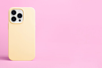 Wall Mural - iPhone 15 Pro in yellow phone case back view isolated on pink background, phone case mockup banner with place for text on the right