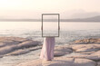 woman holding a frame that surreally reflects the landscape , abstract concept
